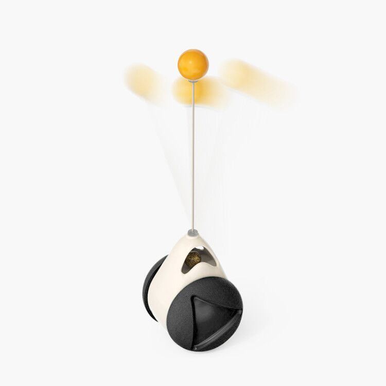 A small robotic toy with a black and off-white body, a long silver pole, and a yellow spherical top, shown on a clean white background with motion blur around the top sphere.
